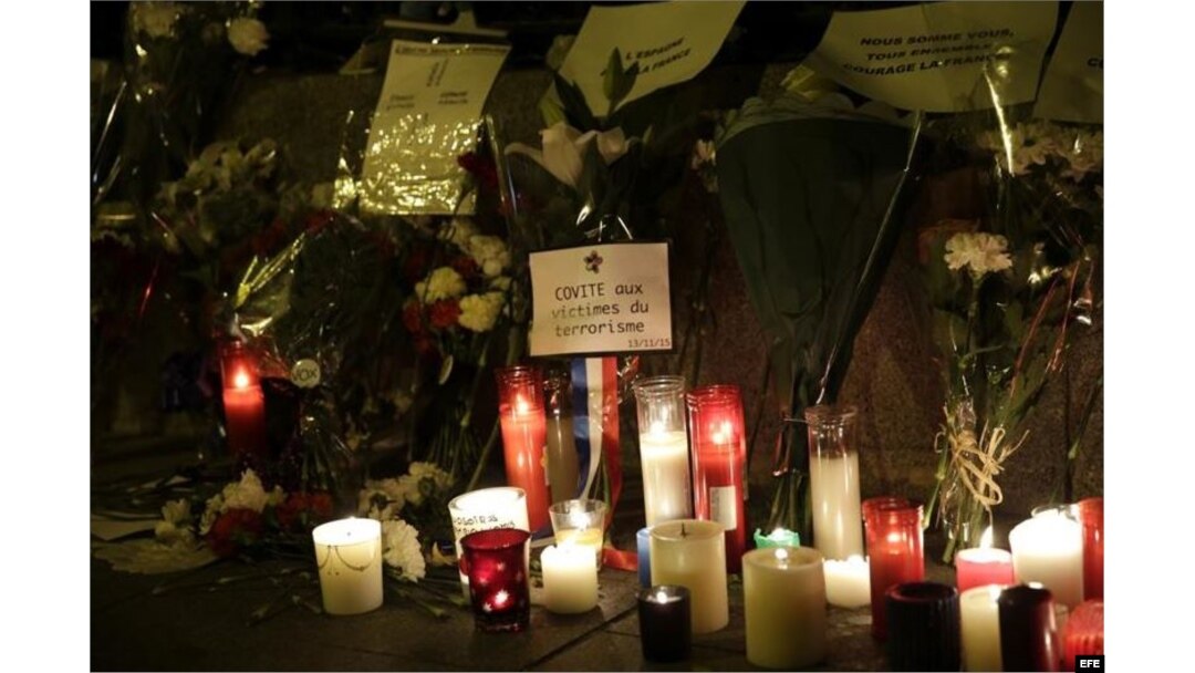 Flores, velas y mensajes depositados ante la puerta de la Embajada de Francia en España, en el centro de Madrid.