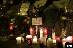 Flores, velas y mensajes depositados ante la puerta de la Embajada de Francia en España, en el centro de Madrid.