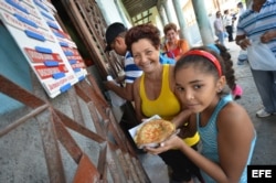 Varias personas compran pizzas en una cafetería gestionada por trabajadores por cuenta propia en La Habana.