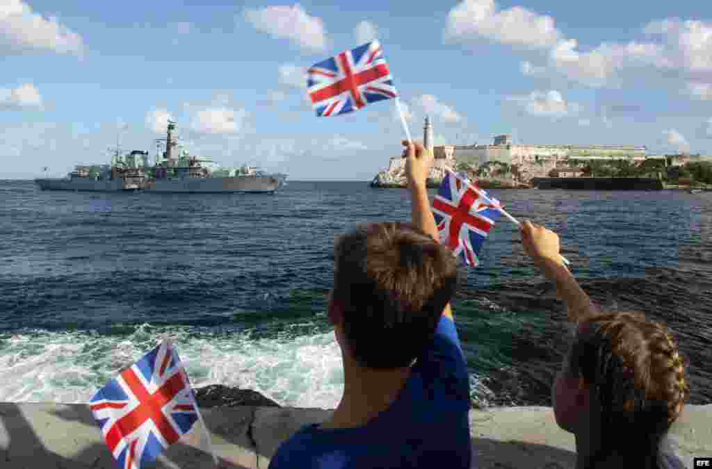 Niños saludan con banderas británicas la llegada de la fragata HMS ARGYLL. 