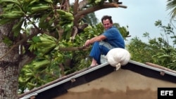 Un pinareño espera sobre el techo de su casa a que baje el nivel del agua. Foto de archivo.