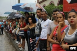 Un grupo de cubanos observa la llegada del presidente de los EEUU Barack Obama a Cuba a través de la señal de televisión captada por un teléfono móvil