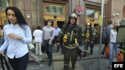  Bomberos rusos y pasajeros abandonan la estación de metro tras el incendio registrado en un túnel de la red de metro, junto a las estación Okhotny Riad, en el centro de Moscú.