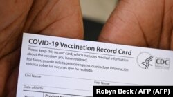 Un trabajador de la salud muestra una tarjeta de registro de vacunación contra el COVID-19 en el Centro de Salud Queens Care, en Los Ángeles, California, el 11 de agosto de 2021. Foto: Robyn Beck / AFP.