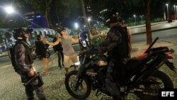 Dos policías interrogan a un joven del que sospechan haberles lanzado una botella durante una protesta para exigir mejores servicios públicos, en Río de Janeiro (Brasil). 