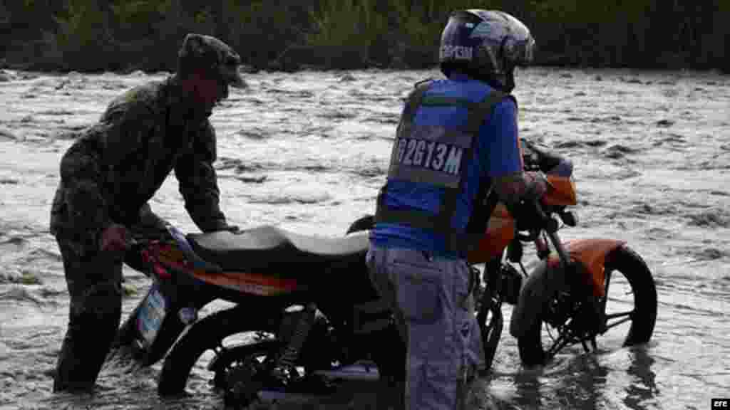Un soldado colombiano ayuda a un motociclista a cruzar el Río Táchira 