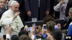 El Papa Francisco saluda a sus seguidores que le fotografían antes de comenzar la audiencia pública. 