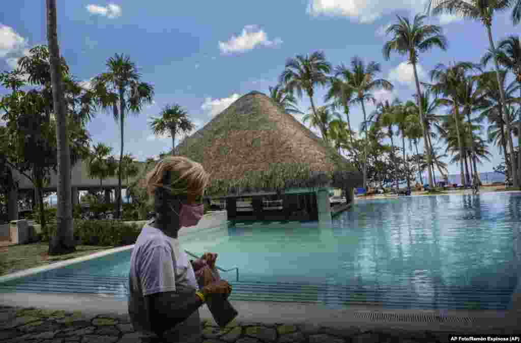 Con una máscara contra la propagación del nuevo coronavirus, una turista camina por el área de la piscina del hotel Meliá Habana en La Habana, Cuba. 11 de febrero de 2021. (AP Foto/Ramón Espinosa)