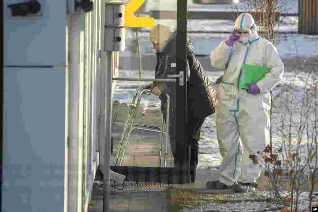 Un trabajador de la salud en Moscú, acompaña a un paciente que sospechan que tiene coronavirus.