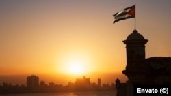 La bandera cubana ondea sobre la Fortaleza de El Morro al atardecer, en La Habana, Cuba.