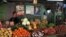  Un hombre vende vegetales en un mercado agrario junto a carteles con las imágenes de Fidel y Raúl Castro. 