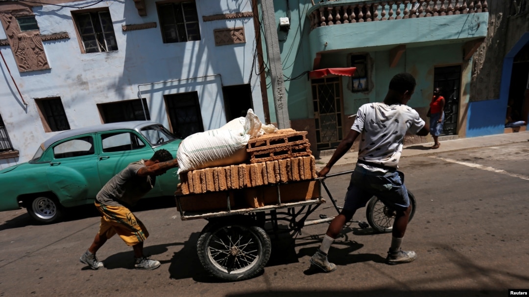 Residentes transportan bloques en una carretilla por una calle de la La Habana. 