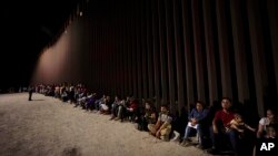 Migrantes esperan junto a un muro fronterizo el martes 23 de agosto de 2022, después de cruzar desde México cerca de Yuma, Arizona (Foto AP/Gregory Bull)