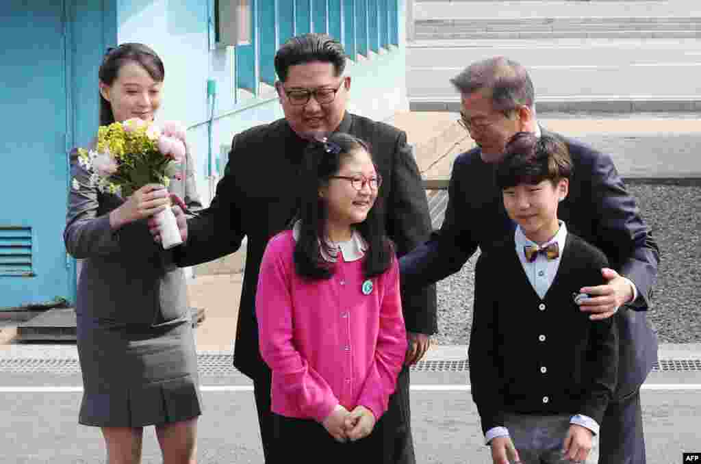 Kim Yo Jong, con un ramo de flores, junto a su hermano Kim Jong Un y el presidente de Corea del Sur, Moon Jae-in, posan con ni&#241;os despu&#233;s de reunirse en la zona desmilitarizada de Panmunjom, el 27 de abril de 2018. (Korea Summit Press Pool/ AFP)