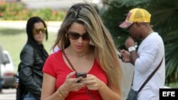 Una joven revisando su teléfono celular en una calle de La Habana.