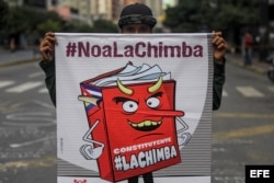 Un hombre sostiene un cartel con una caricatura que representa la Constituyente convocada por Nicolás Maduro.