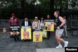 Personas sostienen carteles con las imágenes de Maduro, su esposa Cilia Flores y el ministro del Interior de Venezuela, Diosdado Cabello, mientras esperan para ingresar al Tribunal Federal Daniel Patrick Moynihan en Nueva York.