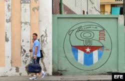 Una pareja camina junto a un cartel con el emblema de los Comités de Defensa de la Revolución (CDR), en La Habana, Cuba.