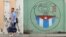 Una pareja camina junto a un cartel con el emblema de los Comités de Defensa de la Revolución en La Habana. 