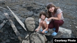 La esposa y la hija del fotógrafo Andrei Parfyonov posan con fragmentos de la estatua de Stalin.