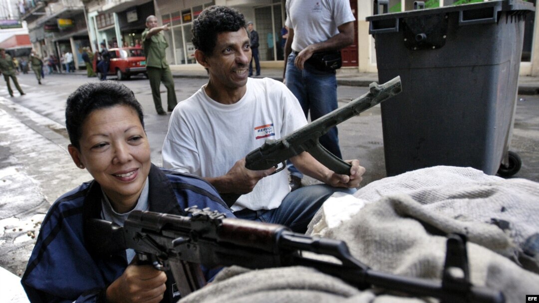 Archivo - Dos civiles permanecen atrincherados, ella con un fusil AKM y él con uno de utilería, en un n “enfrentamiento con el enemigo” en Centro Habana, el Día Nacional de la Defensa de Cuba. 