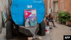 Un cubano descansa junto a un camión cisterna "pipa" donde han colocado un cartel con las figuras de Fidel y Raúl Castro el 9 de abril de 2018. (Archivo)