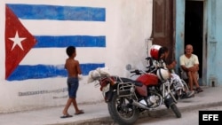 Un niño pasa junto a una pintura de la bandera cubana en una pared, en La Habana, Cuba.