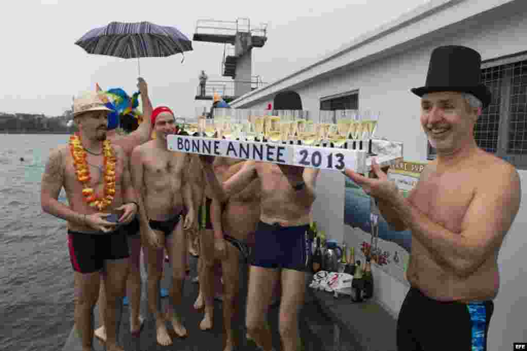 Varios bañistas muestran copas de champán antes de zambullirse en las aguas del Lago de Ginebra (Suiza) para celebra la llegada del nuevo año.