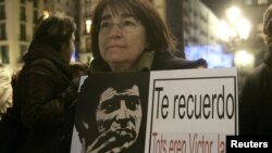An opponent of the late Chilean dictator Augusto Pinochet holds poster of Chilean singer Victor Jara, who was murdered during Pinochet's dictatorship, at Sant Jaume square in Barcelona December 11, 2006. The poster reads, "I remind you, we all were Victo