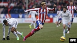 El delantero del Atlético de Madrid Fernando Torres (c) controla el balón ante los defensas del Real Madrid Dani Carvajal (d) y Raphael Varane.
