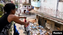 Una mujer cuelga ropa en un tendedero cerca de un montón de basura en la calle, en La Habana, Cuba, 31 de agosto de 2024. REUTERS/Norlys Perez