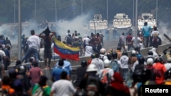 Manifestantes enfrentan los vehículos militares, cerca de la base La Carlota, en Caracas. 