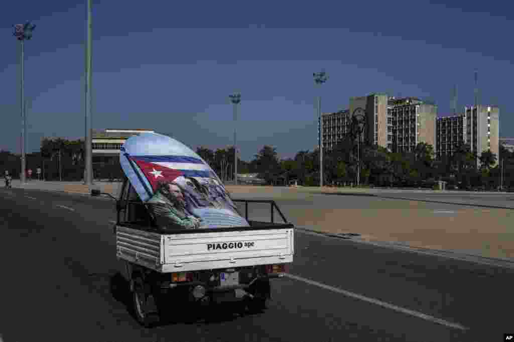 Una moto-camión transporta un póster de Fidel Castro con la bandera de Cuba por la Plaza de la Revolución de La Habana el 2 de marzo del 2021. No se ve un turista en las inmediaciones. (AP Photo/Ramón Espinosa)