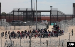 Migrantes hacen fila para ser trasladados por la Patrulla Fronteriza de Estados Unidos después de haber cruzado el río Bravo en El Paso, Texas, visto desde Ciudad Juárez, estado de Chihuahua, México, el 18 de abril de 2024.