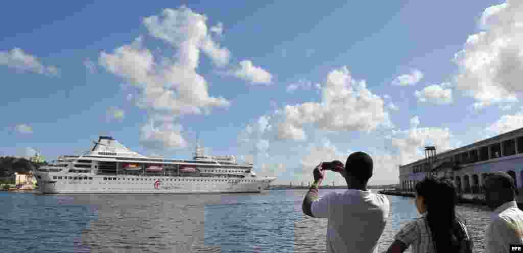 Cubanos le toman fotos al buque Gemini, de la compañía española Happy Cruises, que reanudó el turismo regular de cruceros a Cuba hoy, viernes 12 de noviembre del 2010, en La Habana, después de que esa modalidad de transporte turístico sufrió una important
