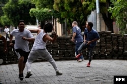 Manifestantes lanzan piedras durante enfrentamientos con la Policia Nacional en los barrios de Managua.