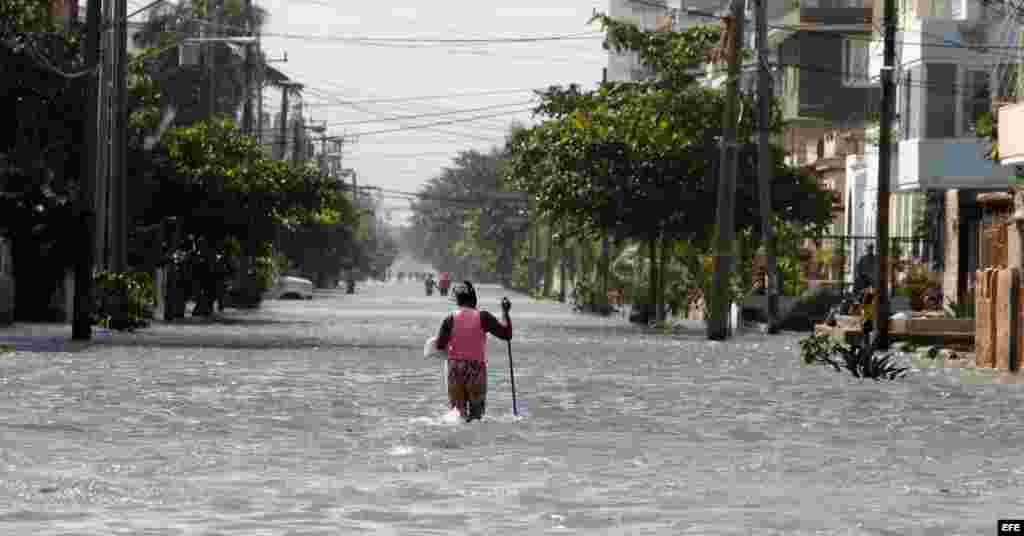 Una mujer camina por una calle inundada de agua de mar hoy, sábado 23 de enero del 2016, en La Habana (Cuba). La Defensa Civil cubana emitió un aviso por las penetraciones del mar en todo el occidente del país. EFE/Ernesto Mastrascusa