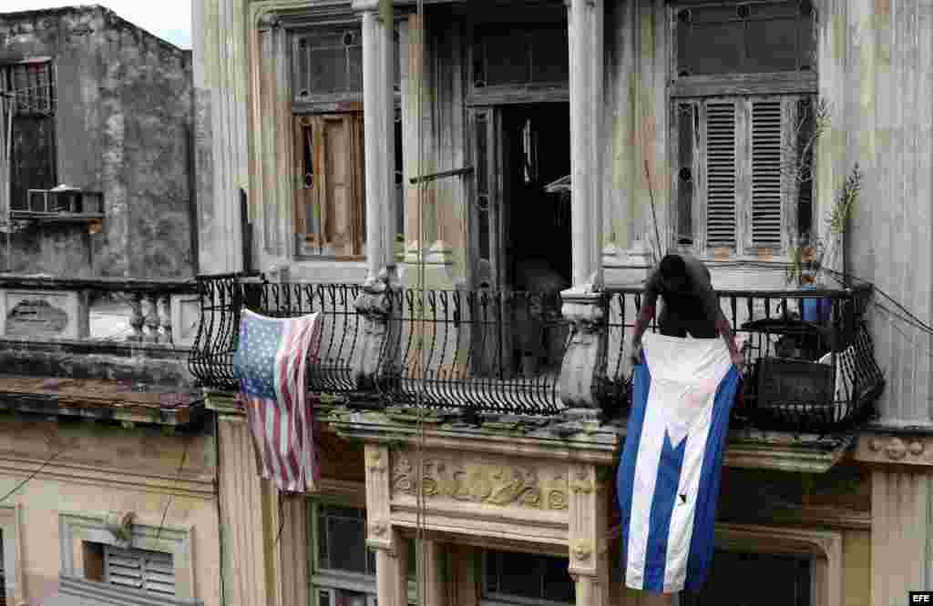 Un hombre cuelga una bandera de Cuba después de colgar la de EE.UU. hoy, lunes 21 de marzo de 2016, en La Habana (Cuba).