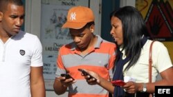 Jóvenes utilizan sus teléfonos celulares en Cuba