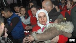Una mujer carga a su hija en un refugio de la Medialuna Roja Siria