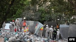 Empleados de la estatal Petróleos Mexicanos (Pemex) colocan lienzos para bloquear la visibilidad al interior del sitio donde ocurrió la explosión, en Ciudad de México. 