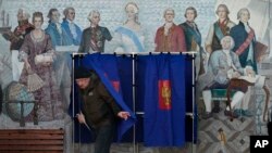 Un hombre sale de una cabina de votación en un colegio electoral ubicado en una escuela durante las elecciones presidenciales en San Petersburgo, Rusia, el sábado 16 de marzo de 2024.