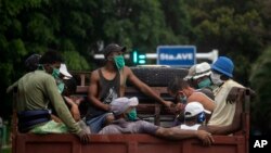Trabajadores con máscaras protectoras por el coronavirus viajan en un camión en La Habana. (AP Photo/Ramon Espinosa)