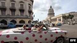 Turistas se pasean en un auto clásico cerca del Capitolio, en La Habana. (Archivo)