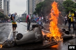 Opositores a Nicolás Maduro queman basura en la vía pública.