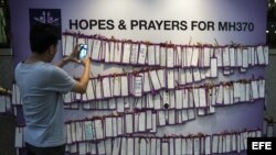 Un joven fotografía mensajes de apoyo a los pasajeros del vuelo desparecido de Malaysia Airlines en un centro comercial en Kuala Lumpur (Malasia).