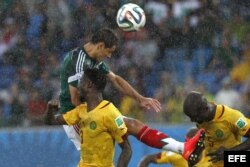El delantero mexicano Javier Hernández (i) cabecea el balón ante los jugadores de Camerún durante el partido México-Camerún, del Grupo A del Mundial de Fútbol de Brasil 2014, en el Estadio das Dunas de Natal, Brasil.