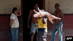 Un hombre carga un cerdo en sus hombros en una calle de La Habana. (Archivo)