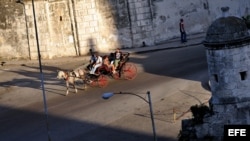 Turistas pasean en un coche de caballos por una avenida de la Habana Vieja. 