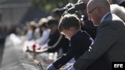 Un niño localiza el nombre de un pariente durante los actos en recuerdo de los fallecidos en los atentados